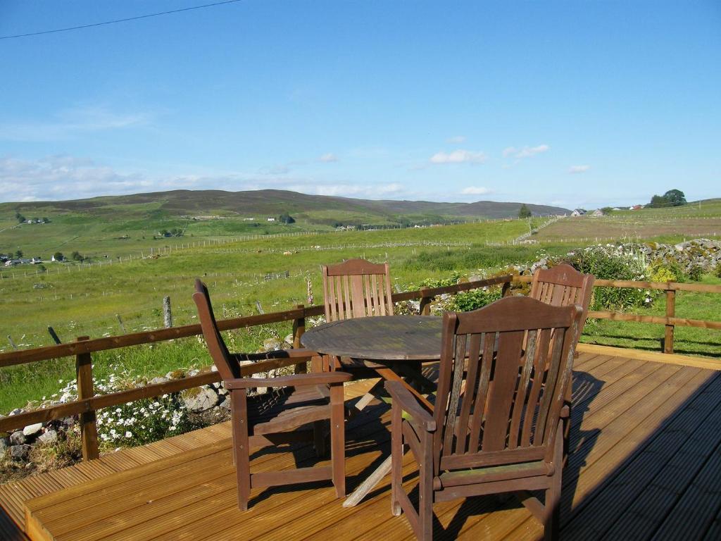 una mesa de madera y 2 sillas en una terraza con un campo en The Barn, en Lairg