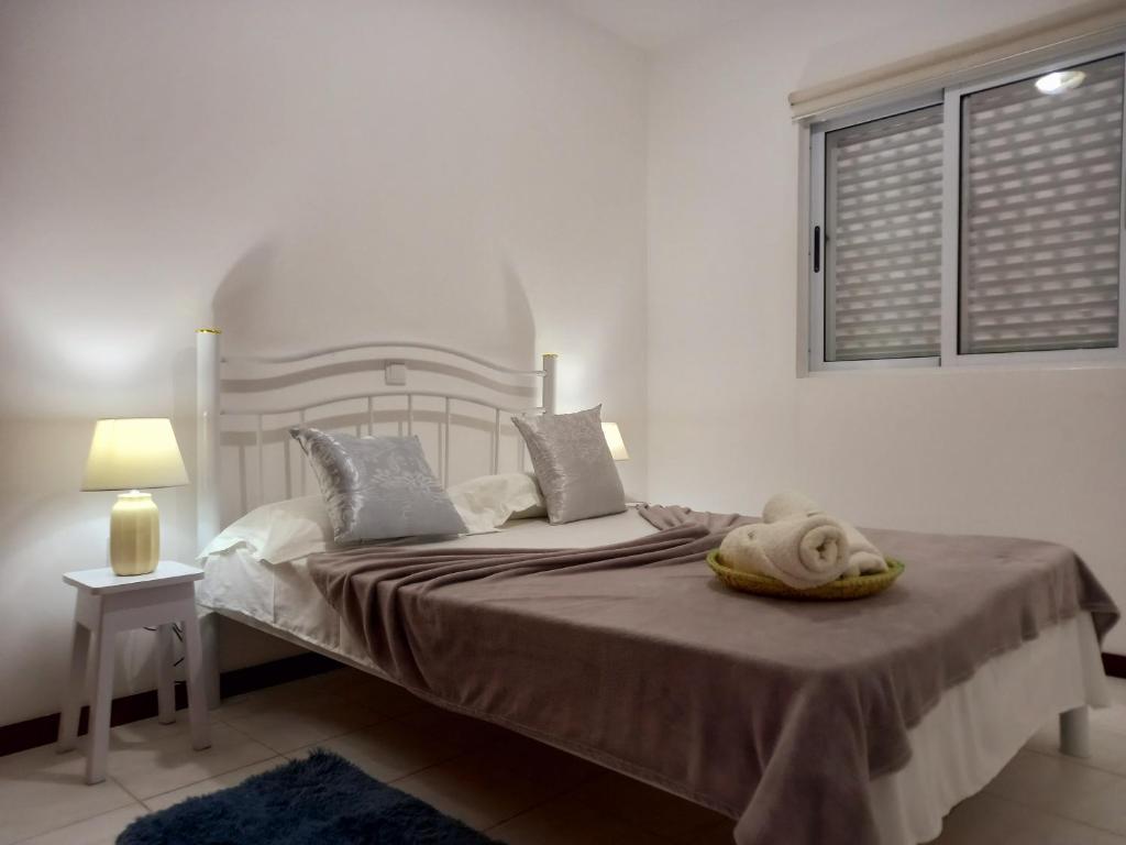 a bedroom with a bed with a blanket and a window at Arco-yris in Ponta do Sol