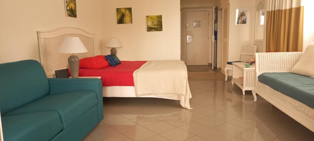 een hotelkamer met een bed en een bank bij F1 vue mer, accès plage, en centre-ville in Le Gosier