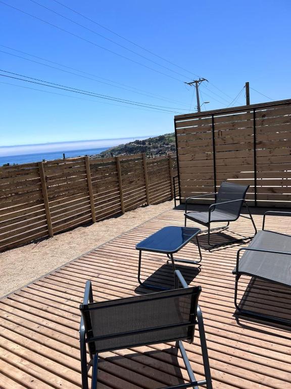 a deck with chairs and tables on the beach at Cabaña Hermosa Maitencillo in Valparaíso