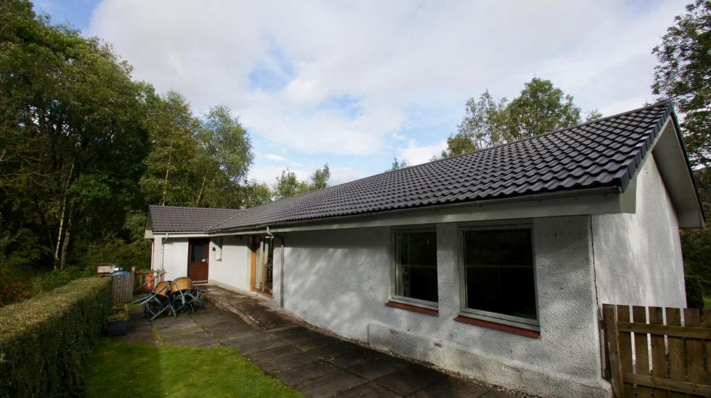 a small white house with a patio in a yard at Allt Beag in Lochearnhead