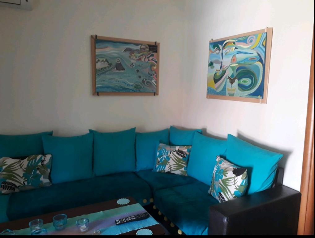 a blue couch in a living room with paintings at Blue lagoon in Skála Foúrkas