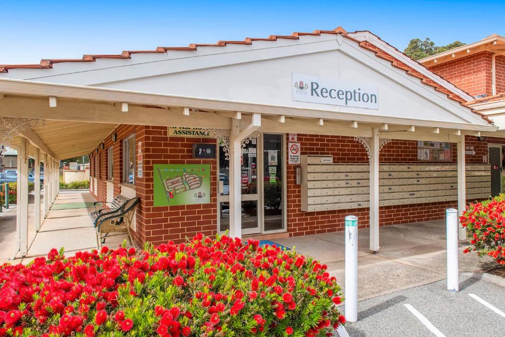 a red brick building with a white awning and flowers at Banksia Tourist Park in Perth