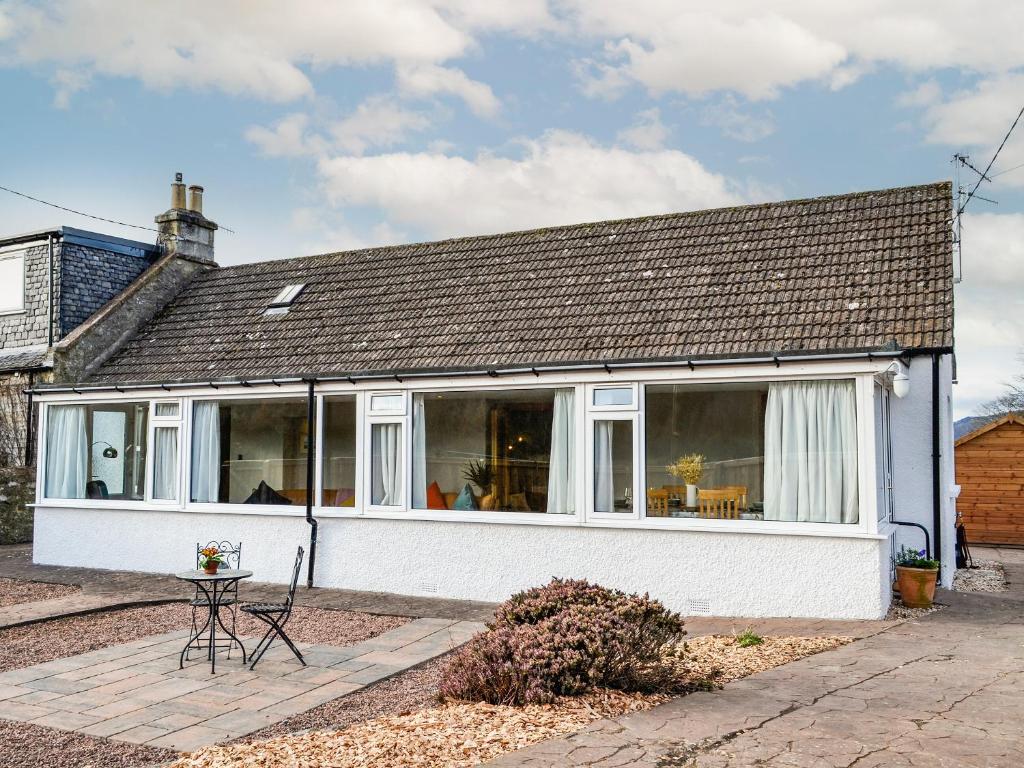 a white house with windows and a table and chairs at Maryland Cottage in Aberargie