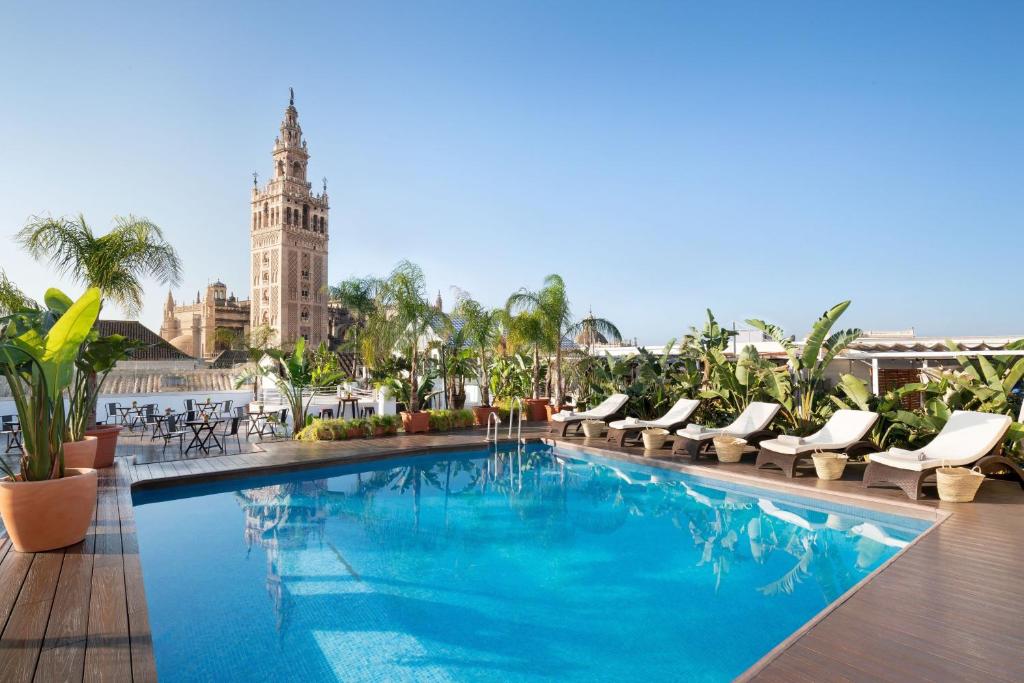 une piscine avec des chaises longues et un bâtiment dans l'établissement Los Seises Sevilla, a Tribute Portfolio Hotel, à Séville