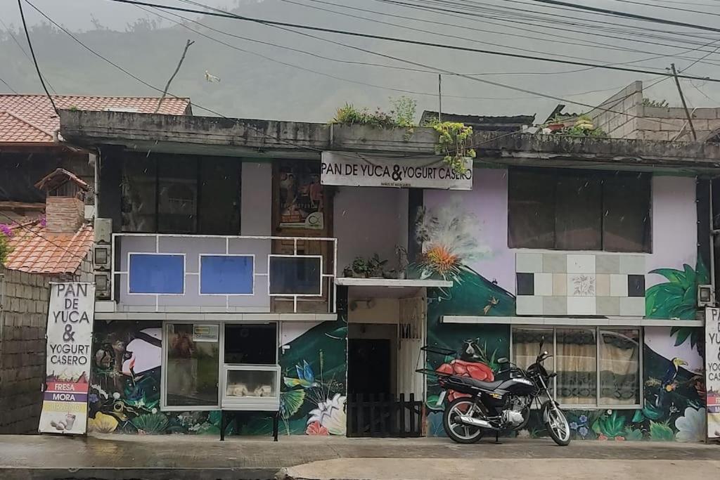 a motorcycle parked in front of a building with graffiti at La Casa del Pan de Yuca Baños in Baños