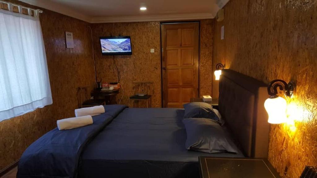 a bedroom with a blue bed with pillows and a television at Homestay Umbai Kelana in Merlimau