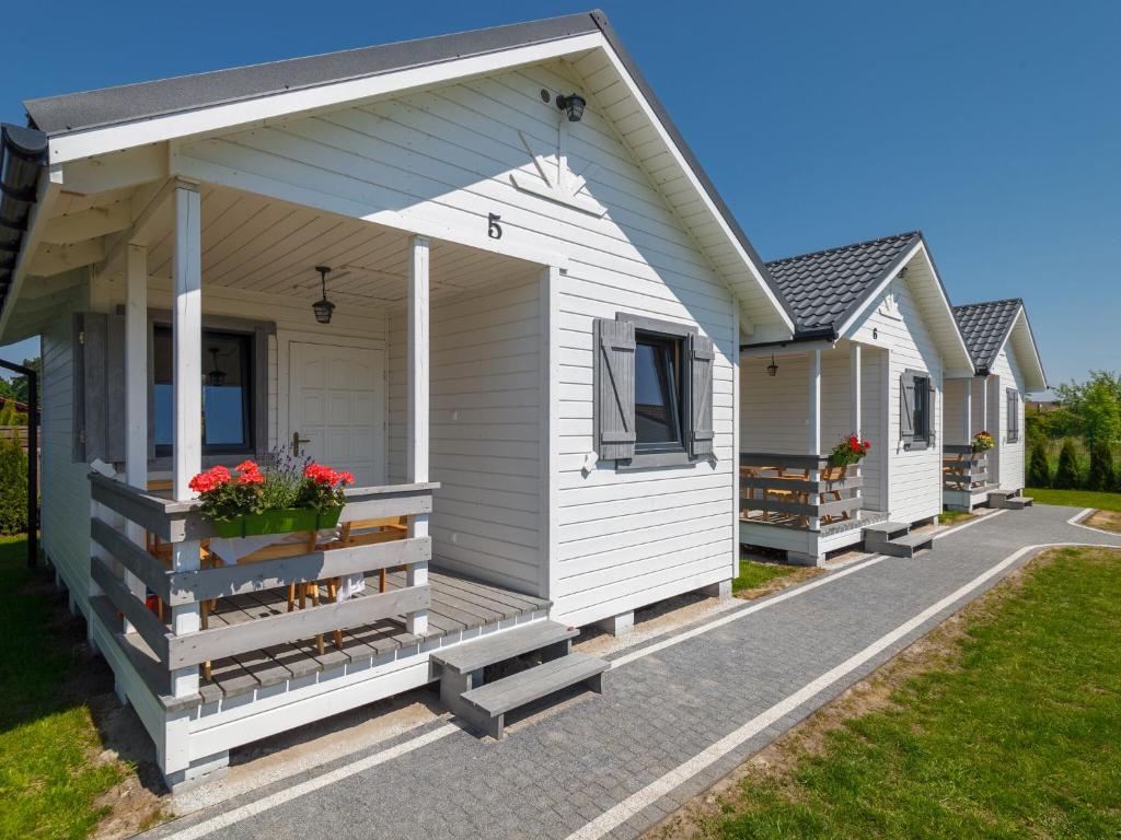a white house with a porch with flowers on it at One-storey holiday houses near the beach, G ski in Gąski