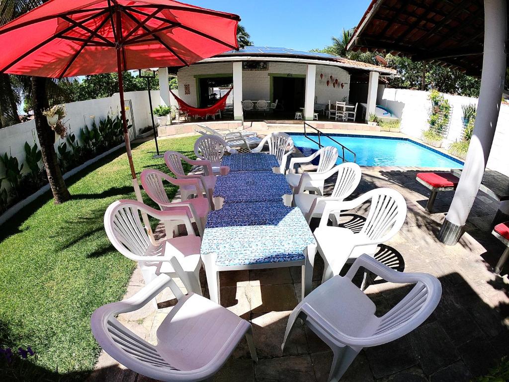 a table and chairs and an umbrella next to a pool at Casa de praia com piscina para família in Sirinhaém