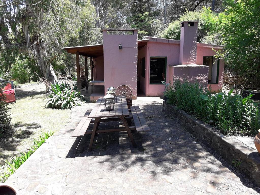 una mesa de picnic frente a una casa pequeña en La Rosadita del Paraje en Villa Yacanto