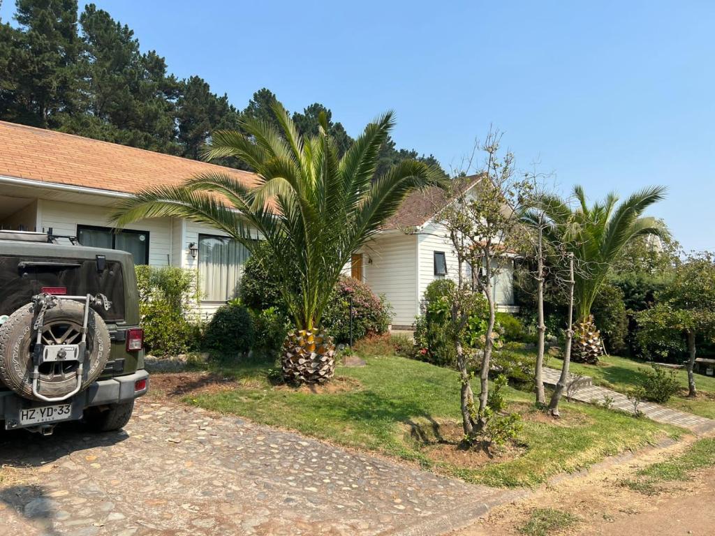 a car parked in front of a house with palm trees at Acogedora casa en Pingueral in Concepción