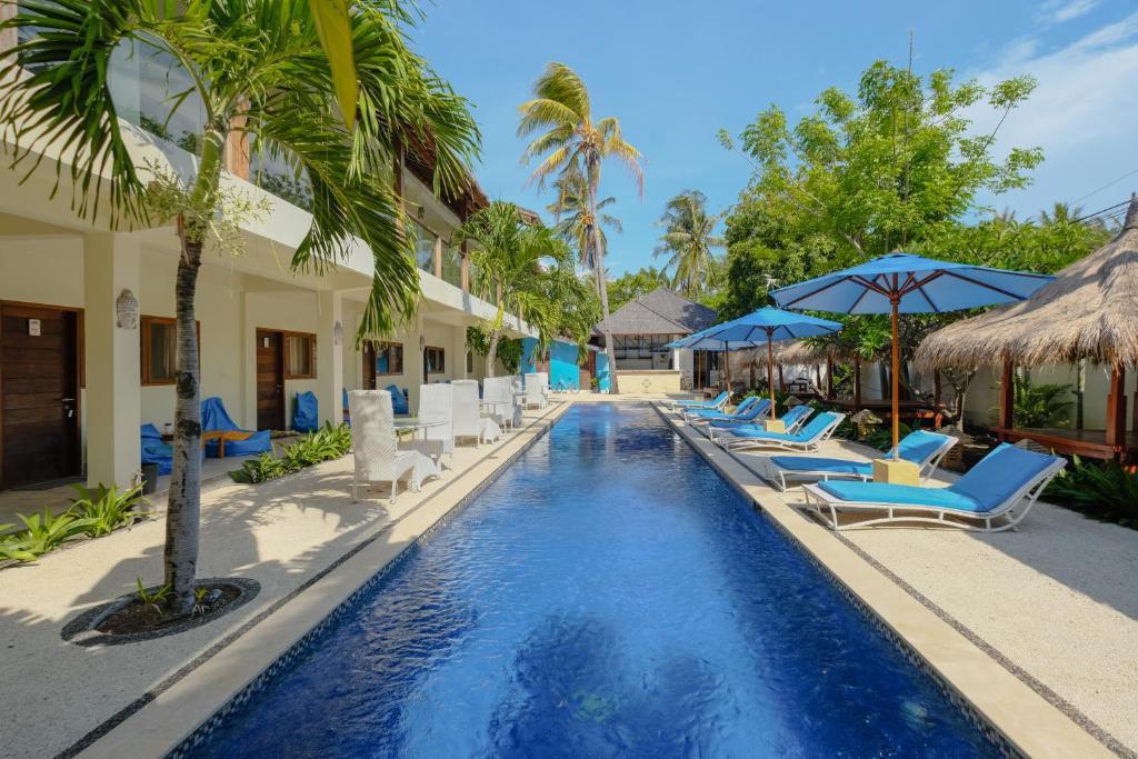 a pool at the resort with lounge chairs and umbrellas at Trawangan Nirvana in Gili Trawangan