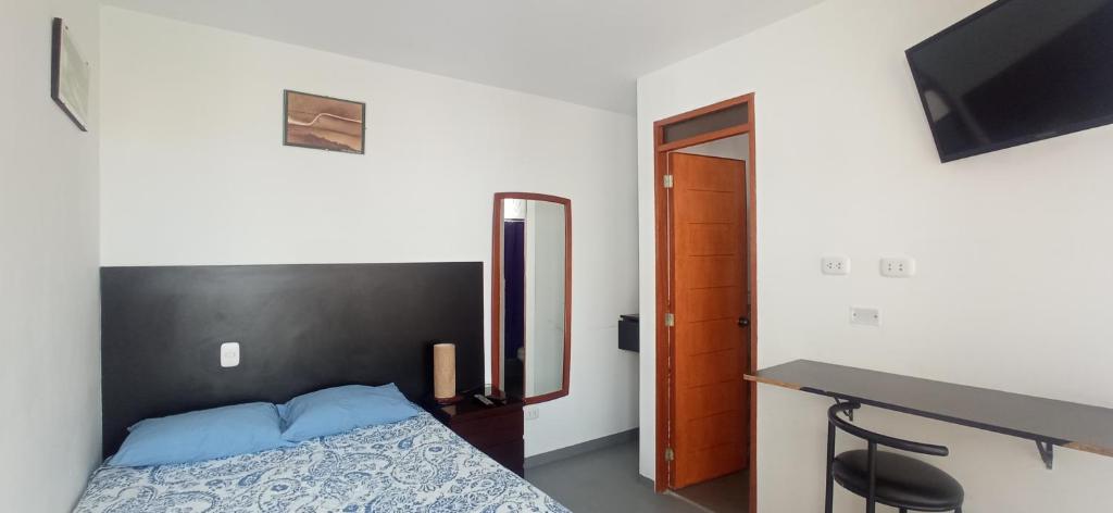 a bedroom with a bed with a black headboard and a desk at Bravo Hostels: Surf House in Punta Hermosa