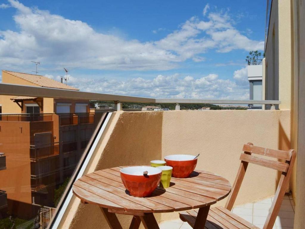 - une table en bois sur un balcon avec 2 tasses dans l'établissement Narbonne Plage : Appartement 2 Chambres, Balcon, Ascenseur - FR-1-229B-90, à Narbonne