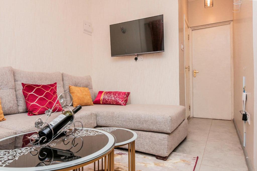 ein Wohnzimmer mit einem Sofa und einem TV in der Unterkunft StayEasy Tsavo in Nairobi