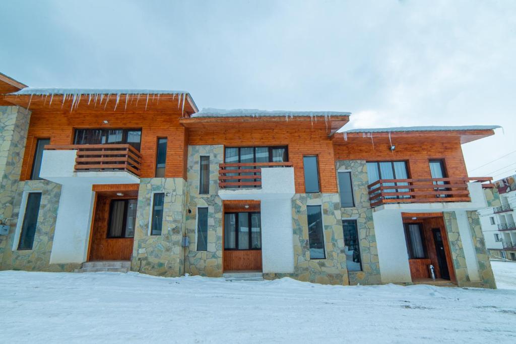 duży ceglany budynek z śniegiem przed nim w obiekcie Gio’s Family house w mieście Bakuriani