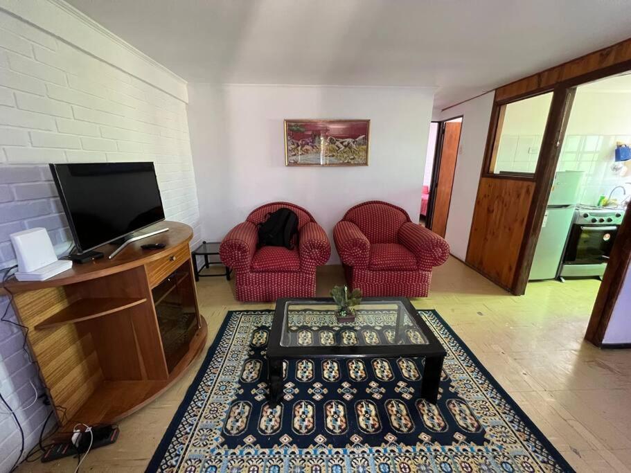 a living room with two red chairs and a television at Casa de veraneo in Los Vilos