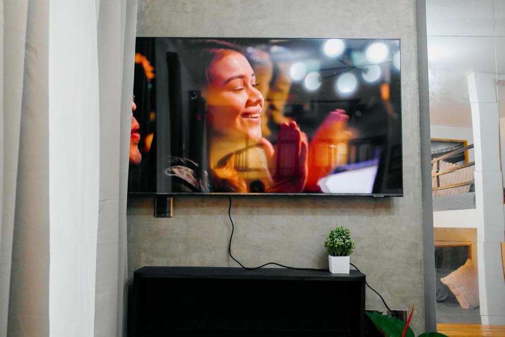 TV de pantalla plana colgada en la pared en Antara-QueenBed-Balcony-HotShower-WorkCoffee Station-FullKitchen, en Talisay
