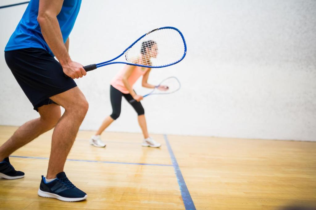 two people playing a game of tennis on a court at ERTH Abu Dhabi Hotel in Abu Dhabi