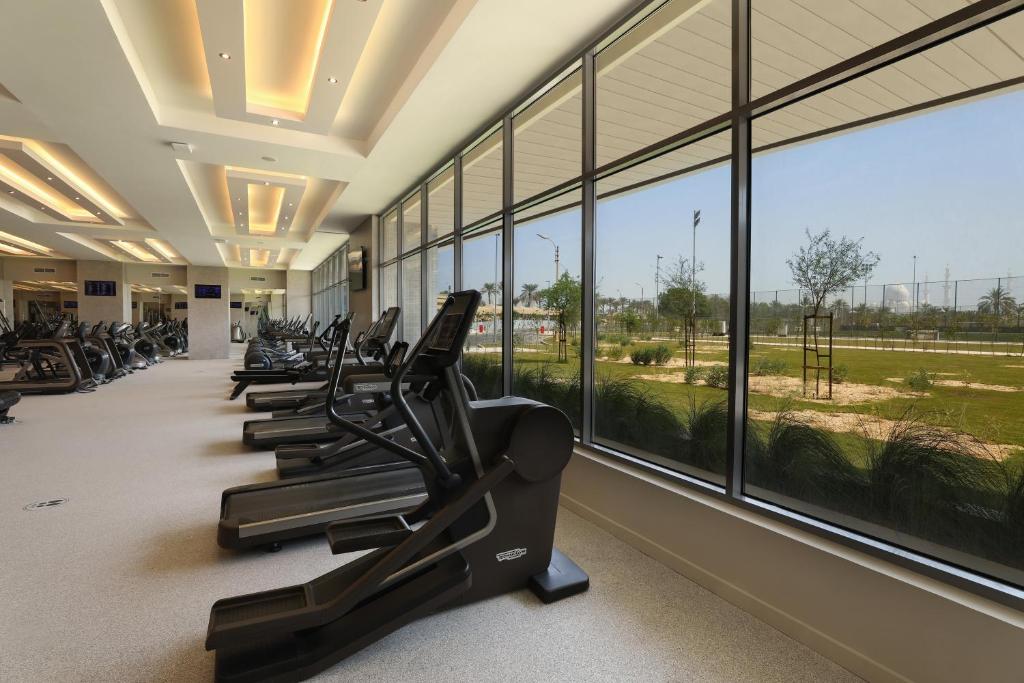 a row of treadmills in a gym with windows at ERTH Abu Dhabi Hotel in Abu Dhabi