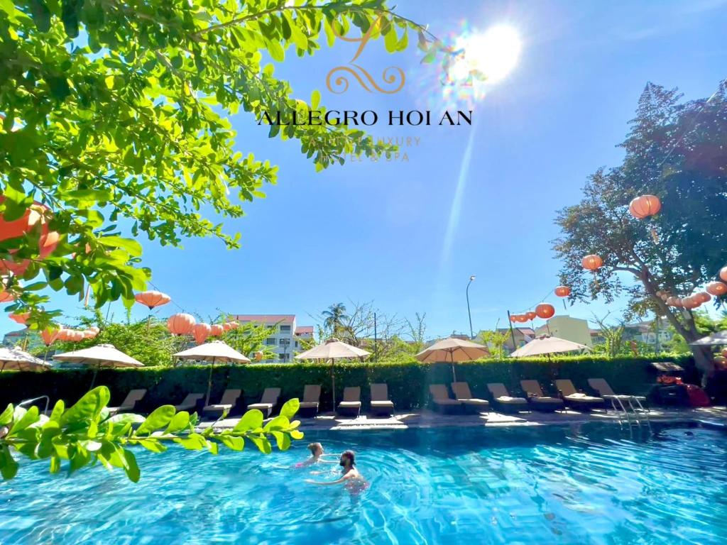 una piscina en un complejo con gente en el agua en Allegro Hoi An . A Little Luxury Hotel & Spa, en Hoi An