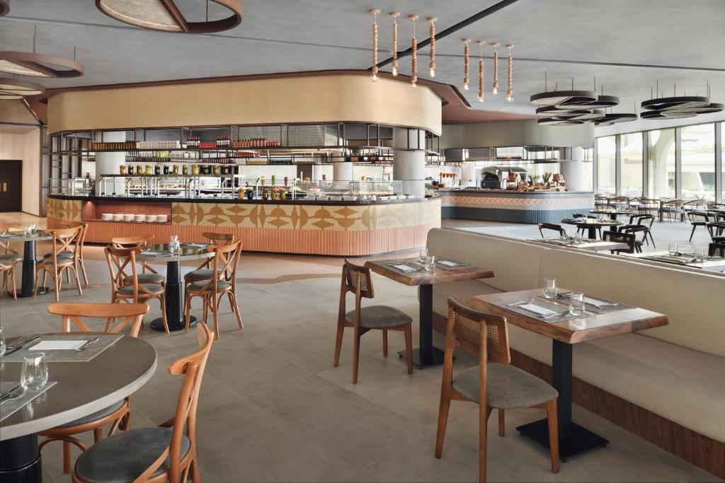 a restaurant with tables and chairs and a counter at ERTH Abu Dhabi Hotel in Abu Dhabi