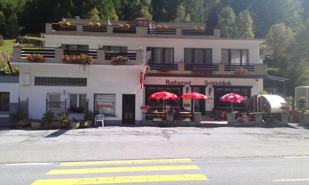 a white building with red umbrellas in front of it at Pension Schönblick in Saas-Grund
