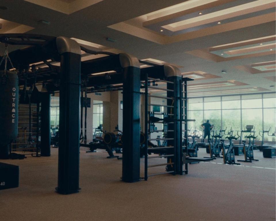 a gym with rows of exercise equipment in a building at ERTH Abu Dhabi Hotel in Abu Dhabi