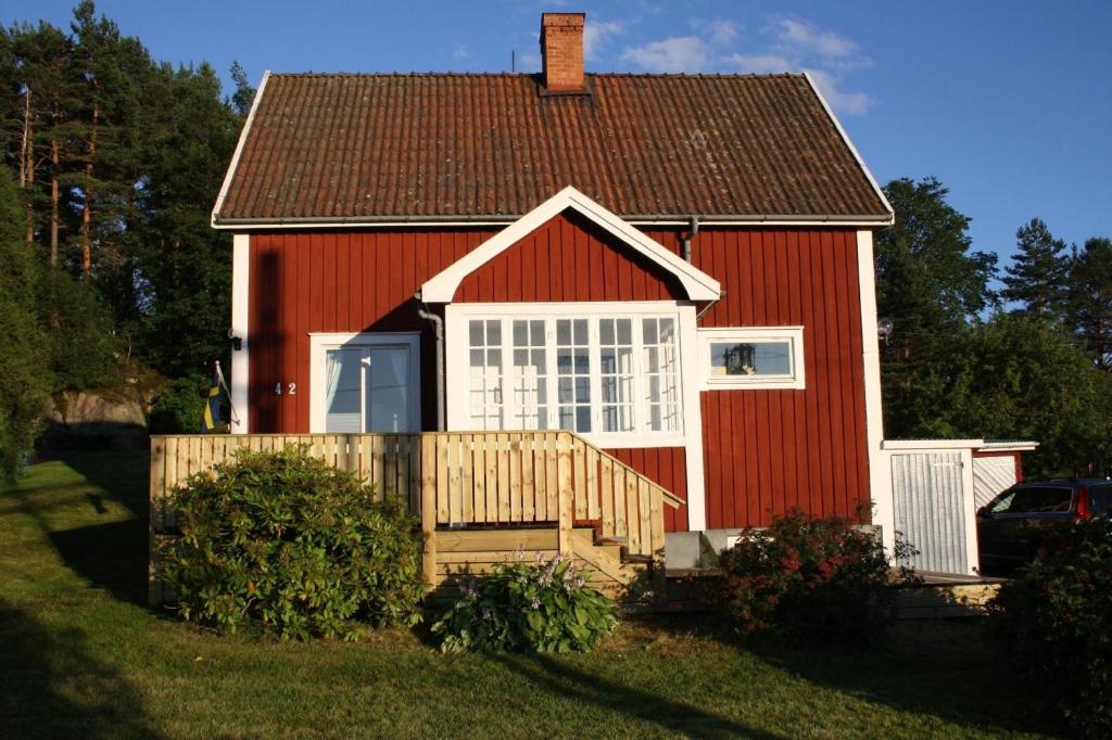 a red house with a wooden fence in front of it at Ferienhaus in Storfors mit Großem Garten in Storfors