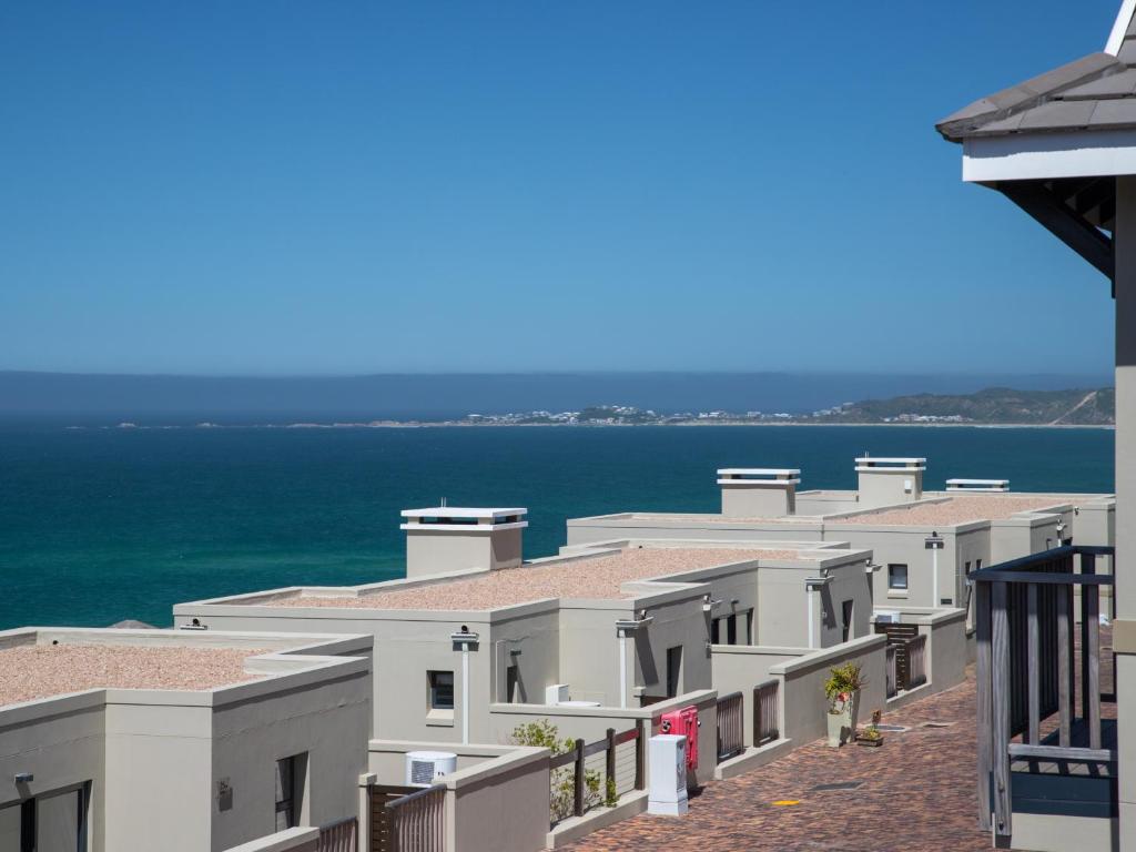 a row of white buildings with the ocean in the background at Brenton Haven Beachfront Resort in Knysna