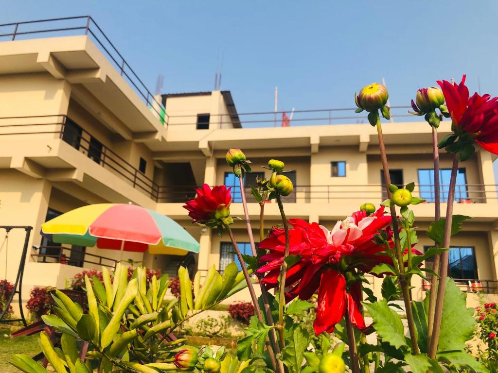 a building with an umbrella and flowers in front of it at Hotel Happy Land in Chitwan