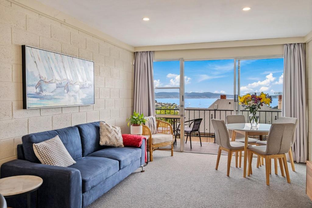 - un salon avec un canapé bleu et une table dans l'établissement SOHO apartment with river views stroll cafes, à Hobart