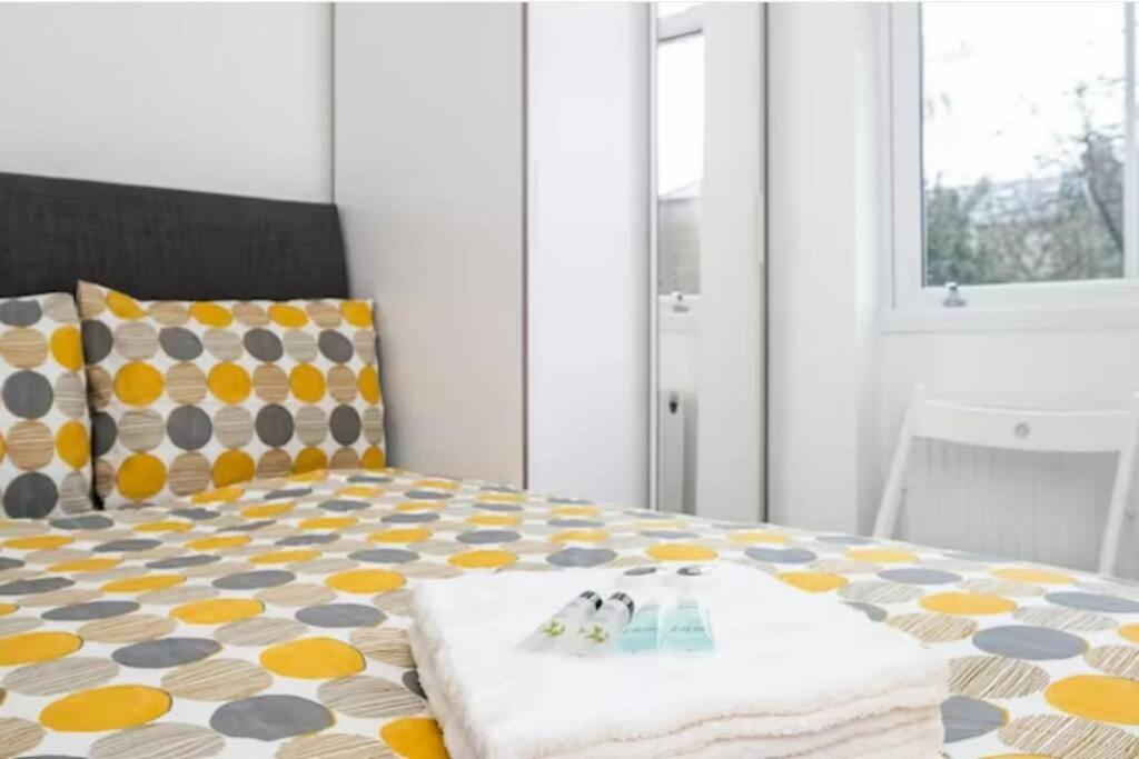 een slaapkamer met een bed met een geel en grijs patroon bij Victorian Functional Accommodation 5Min Walk From Tufnell Park in Londen