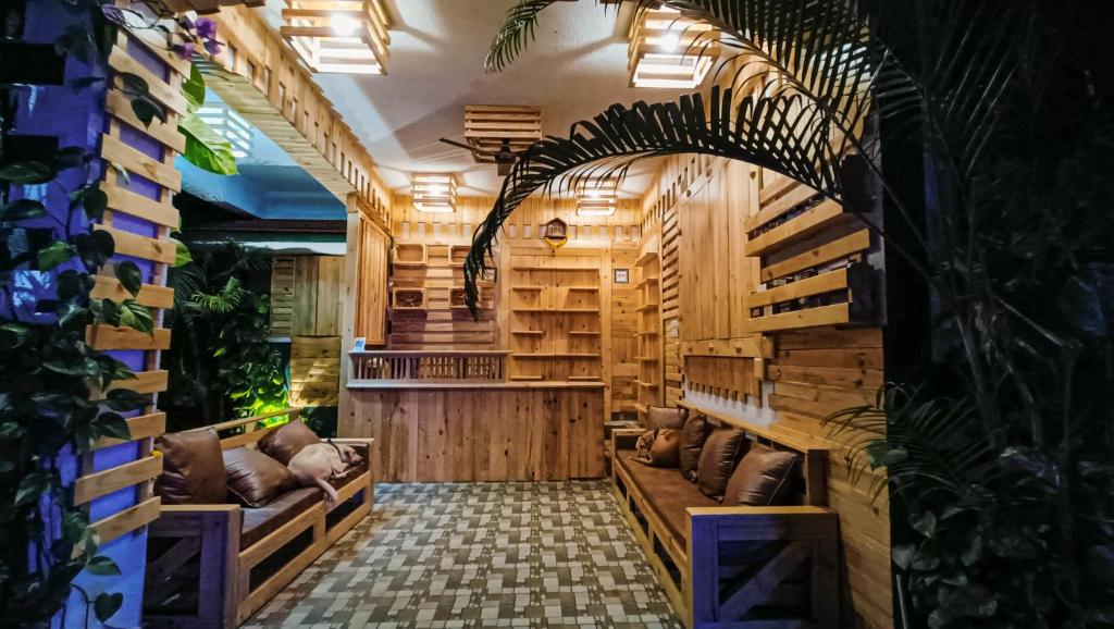 a restaurant with wooden walls and couches and plants at Green Nest Hostel, Baga - Arpora in Arpora