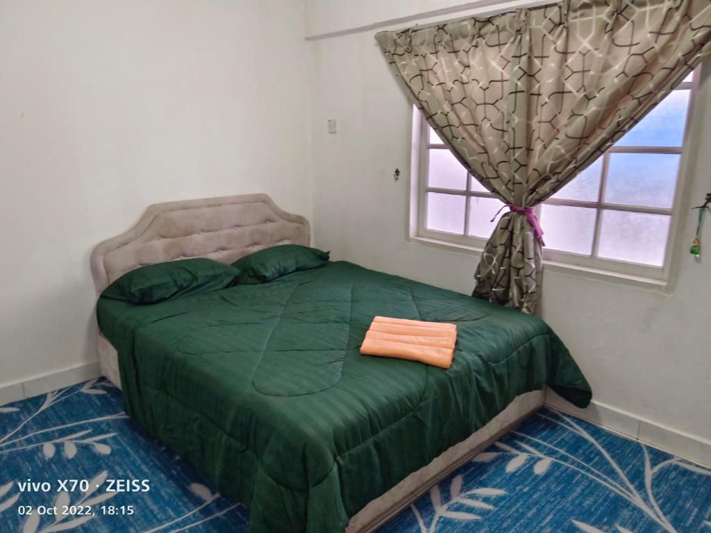 a bedroom with a green bed with a window at Bani's Penthouse (Homestay Cameron Highlands) in Tanah Rata