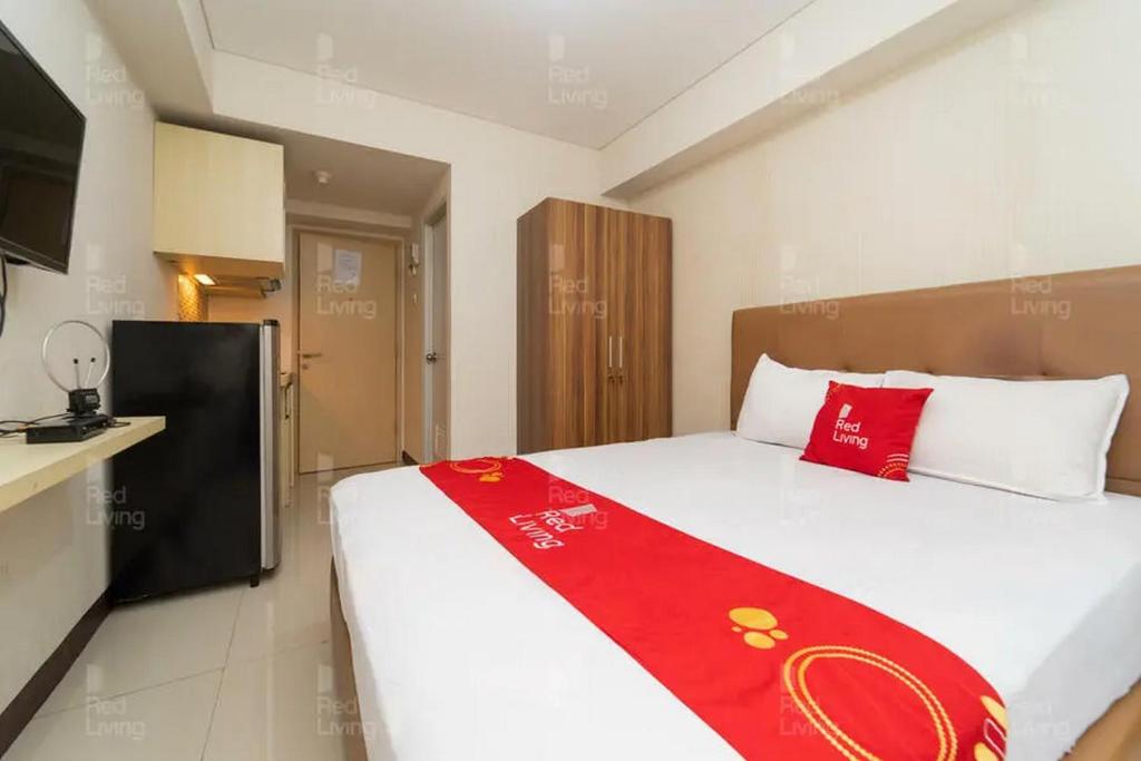 a bedroom with a large bed with a red blanket at RedLiving Apartemen 19 Avenue - Amanah Room in Tangerang