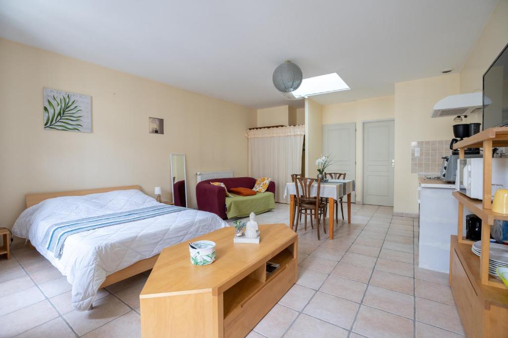 ein Schlafzimmer mit einem Bett und einem Tisch sowie eine Küche in der Unterkunft L'Arbre Rouge & L'Arbre Vert in Jonzac