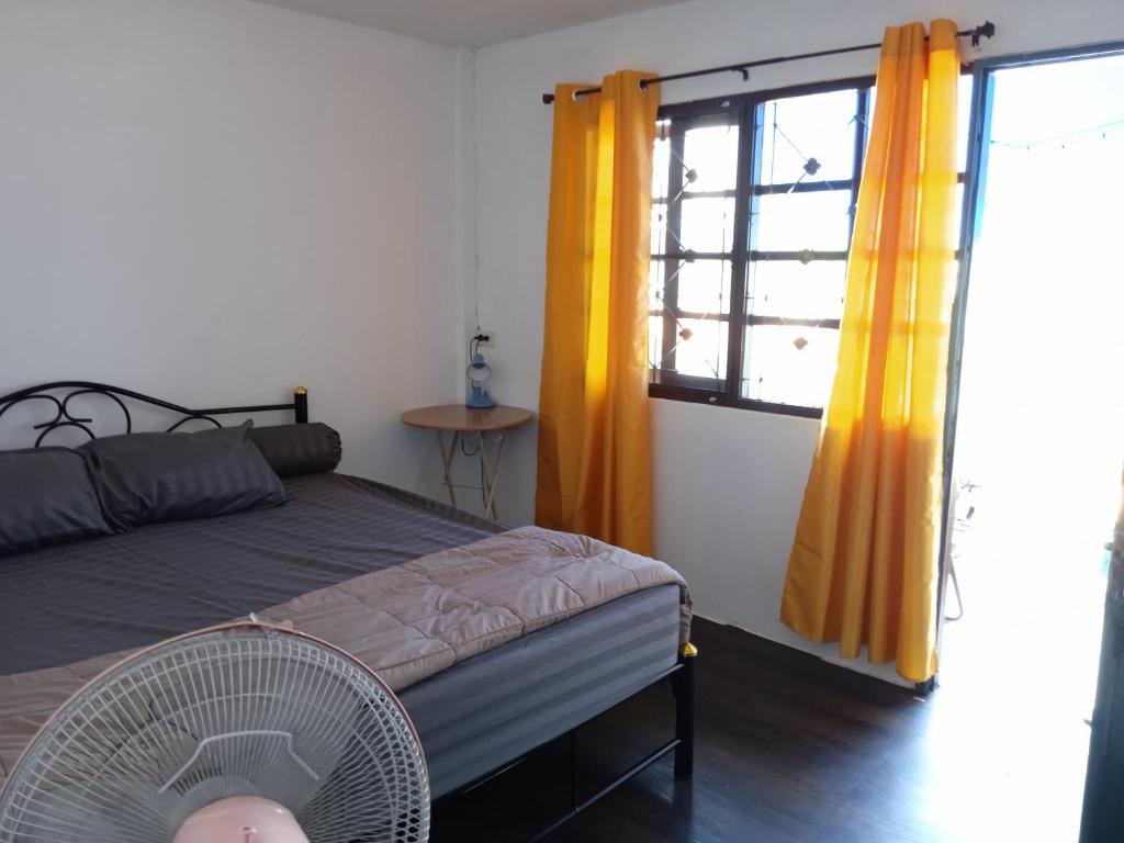 - une chambre avec un lit et une fenêtre avec des rideaux jaunes dans l'établissement ban noo, à Ban Ko