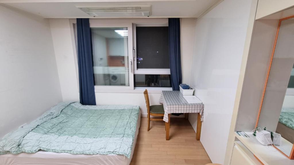 una piccola camera con letto, sedia e finestra di New world hwani House a Seul