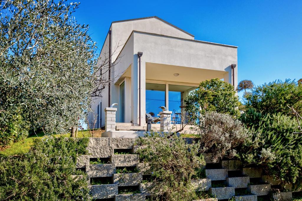 una casa en una colina con árboles y arbustos en Villa Il Poggino - Modern House, en Foiano della Chiana