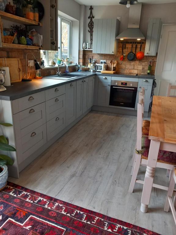 a kitchen with white cabinets and a wooden floor at Escape to the Country in wonderful Worcestershire in Ombersley