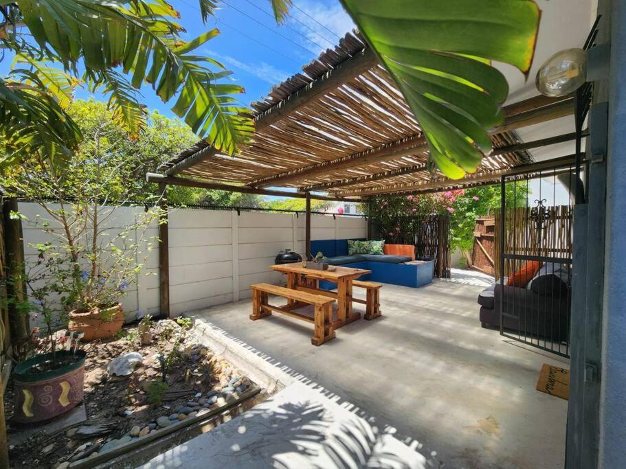 a patio with a wooden picnic table under a pergola at Spacious cottage near Bloubergstrand beach in Cape Town