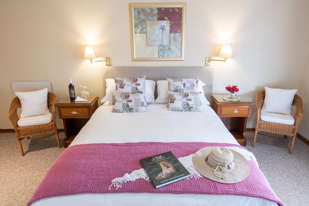 a hotel room with a bed with a hat on it at Hillwatering Country House in Sabie