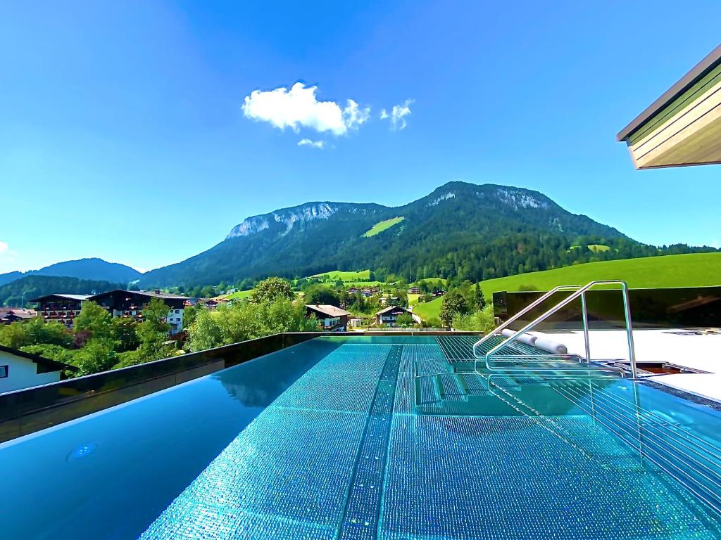 Ein Swimmingpool mit einem Berg im Hintergrund in der Unterkunft Der Postwirt in Söll