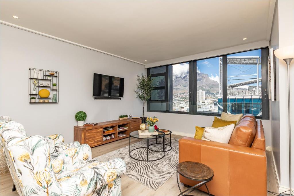 uma sala de estar com um sofá e uma mesa em Beautiful Family Apartment with amazing views @ 16 on Bree em Cidade do Cabo