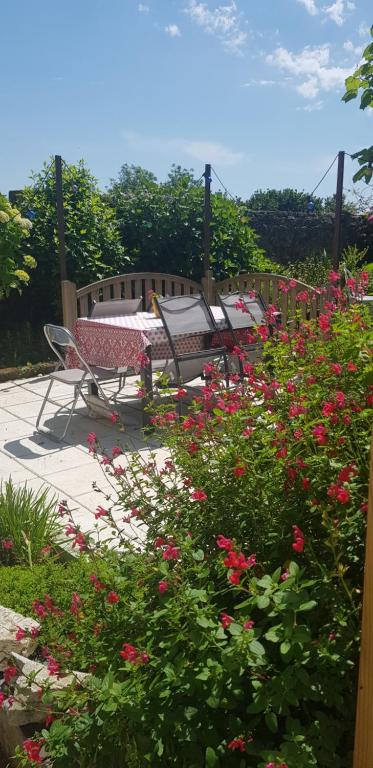 a garden with a table and chairs and flowers at Maison Papillons in Plomodiern