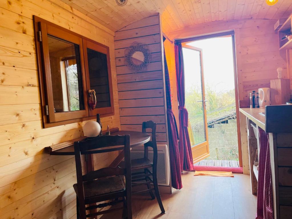 ein kleines Esszimmer mit einem Tisch und einem Fenster in der Unterkunft La Rouloulotte in Durbuy