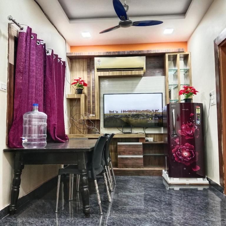 a dining room with a table and a television at Vijayanagara Home Stay in Hampi