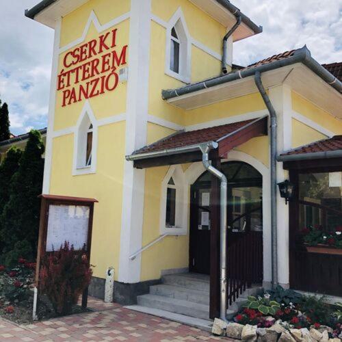 un edificio blanco y amarillo con un letrero. en Cserki Panzió Balatonfőkajár, en Balatonfőkajár