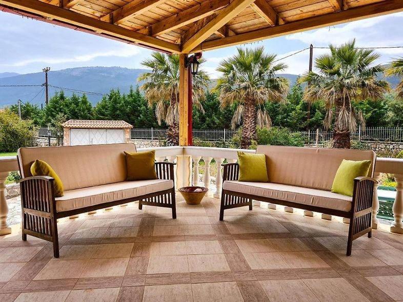 dos bancos sentados en un patio con palmeras en Villa Kostoula, en Karavomylos